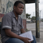 Trabalhador afastado por auxílio-doença por depressão e ansiedade esperando no ponto de ônibus