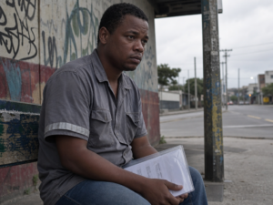 Trabalhador afastado por auxílio-doença por depressão e ansiedade esperando no ponto de ônibus